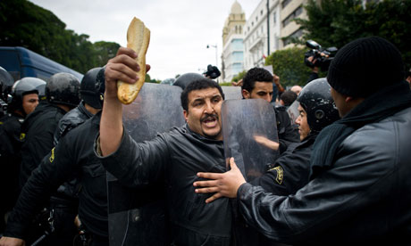 A Tunisian protester holding bread confronts riot policemen during a demonstration in Tunis on January 18, 2011. Photograph: Martin Bureau/AFP/Getty Images