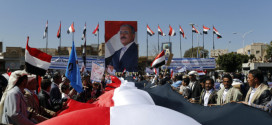 Supporters of Yemen's former President Ali Abdullah Saleh hold a huge Yemeni flag next to a poster of Saleh as they rally in his support in Sanaa