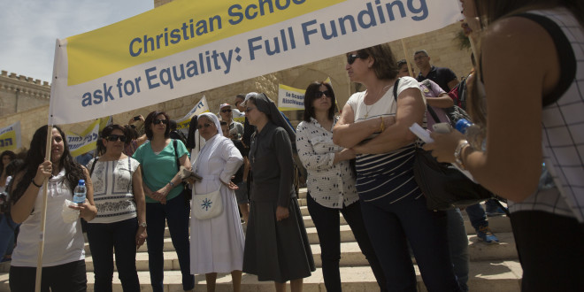 In this photo taken Wednesday, May 27, 2015, Arab Israeli Christians hold signs during a demonstration in front of the education ministry in Jerusalem. (AP Photo/Sebastian Scheiner)